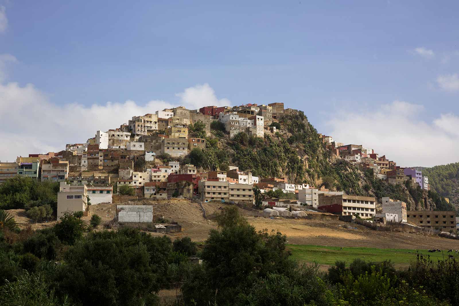 Moulay Idriss is reachable by just a pair of roads and spreads across two foothills of Mount Zerhoun, at the base of the Atlas Mountains.