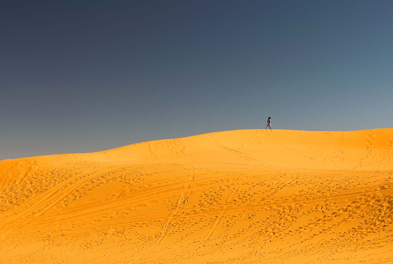 A berber walks along the sand dunes of Erg Chebbi.