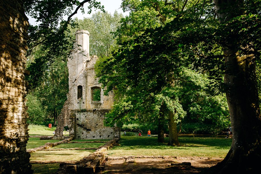 Old ruined buildings through the trees beside a small river