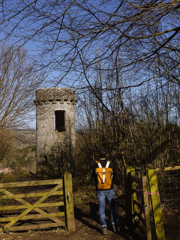 Standing in front of a folly tower at Box Hill in front of an old wooden gate. 