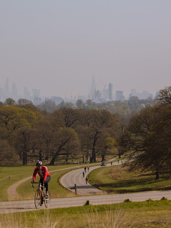 A cyclist on a trail near Richmond Park with the London skyline in the background