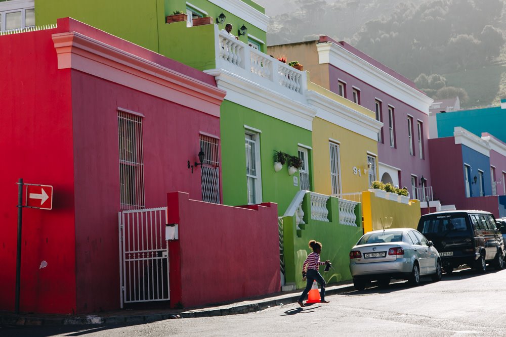 Girl walks in front of colourful houses in Cape Town