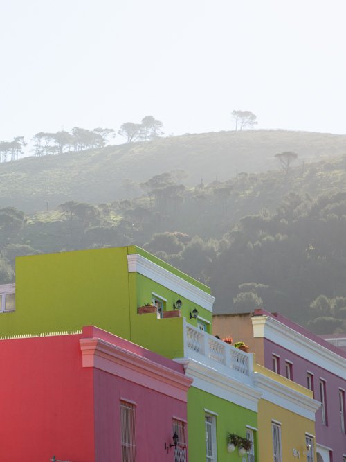 Green, yellow and red houses in front of mountains