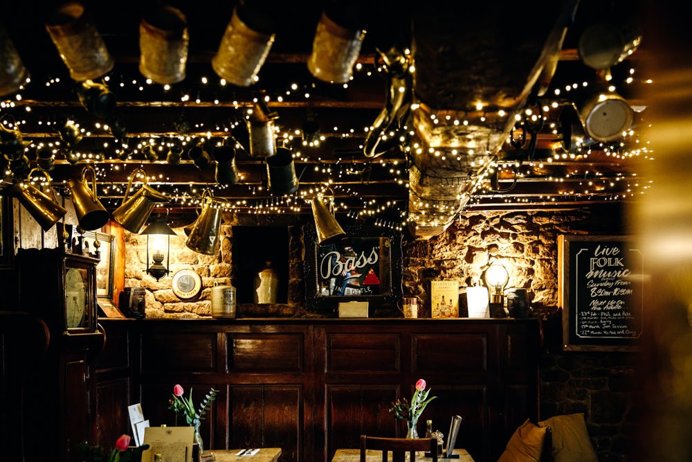dark pub interior with fairy lights hanging from the ceiling beams