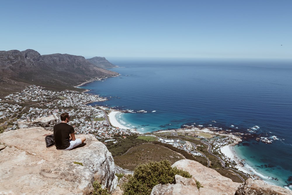 man sitting on a rock overlooking a stunning coastal view